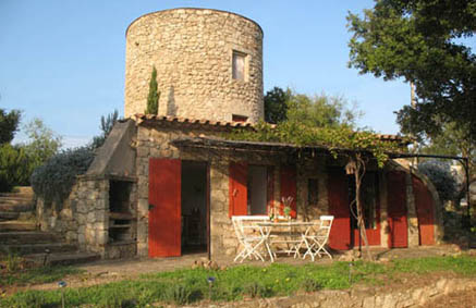 Moulin des Oliviers viewed from the pool. South facing terrace with white table and 4 chairs. 